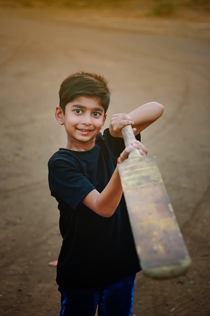 Bambino indiano rurale che gioca cricket