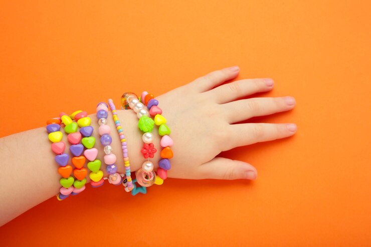 Bambino indossa braccialetti sulle mani Bambini gioielli a perle fatti a mano su sfondo arancione