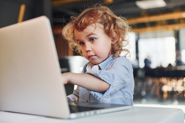 Bambino intelligente in abiti casual che utilizza il laptop per scopi educativi o per divertimento