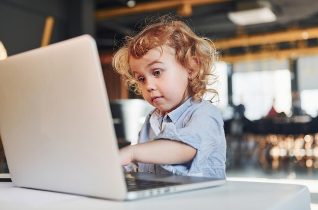 Bambino intelligente in abiti casual che utilizza il laptop per scopi educativi o per divertimento