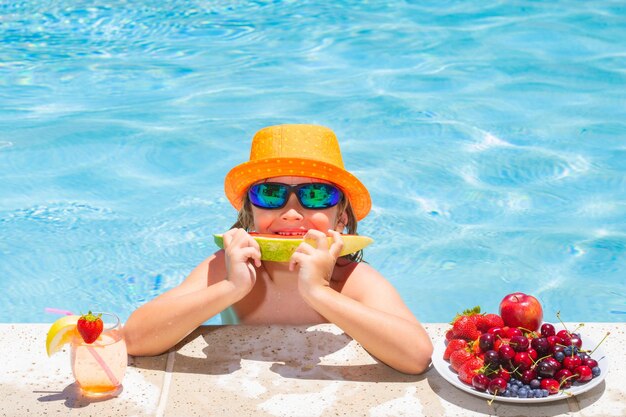 Bambino mangia anguria Kid mangiare frutta estiva sulla piscina watter Bambino in piscina a giocare in acqua d'estate Vacanza e in viaggio con i bambini