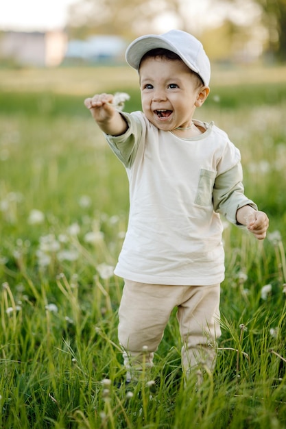 bambino nel parco, bambino felice che gioca con un dente di leone.