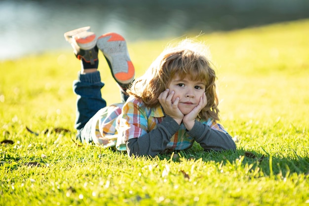 Bambino nel parco bambino primaverile all'aperto sdraiato sull'erba estate ragazzo cammina bambini adattamento