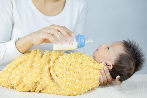 Bambino neonato d'alimentazione della madre del primo piano dal biberon