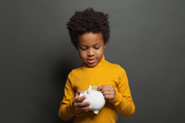 Bambino nero che mette moneta in banca