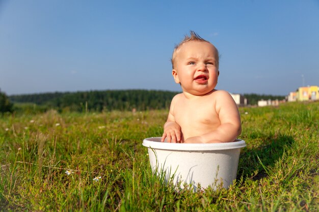 Bambino nudo biondo dolce sveglio che si siede nel bacino