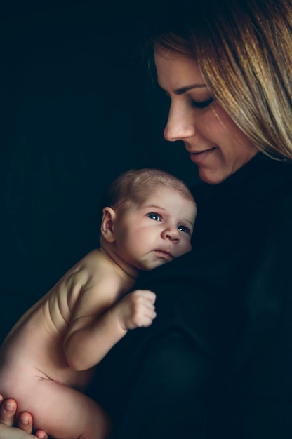 Bambino nudo in posa tra le braccia di sua madre