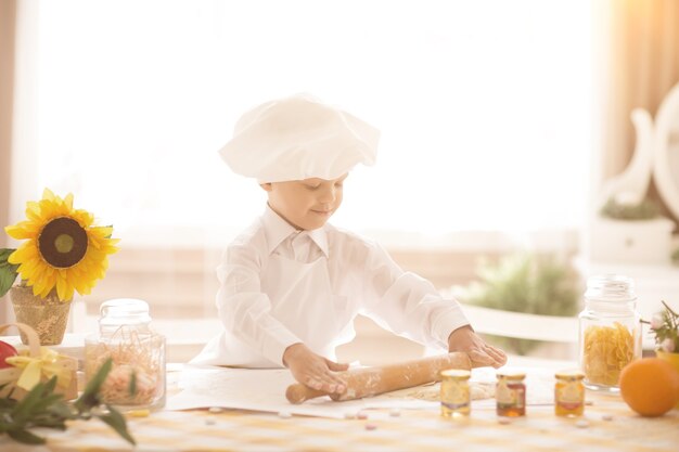 bambino piccolo in forma di cuoco stende la pasta