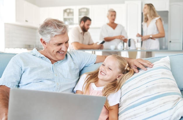 Bambino portatile e nonno con video comici su Internet e il divano del soggiorno di casa loro Ragazza con il sorriso per il servizio di abbonamento su tecnologia con film divertenti e un uomo anziano