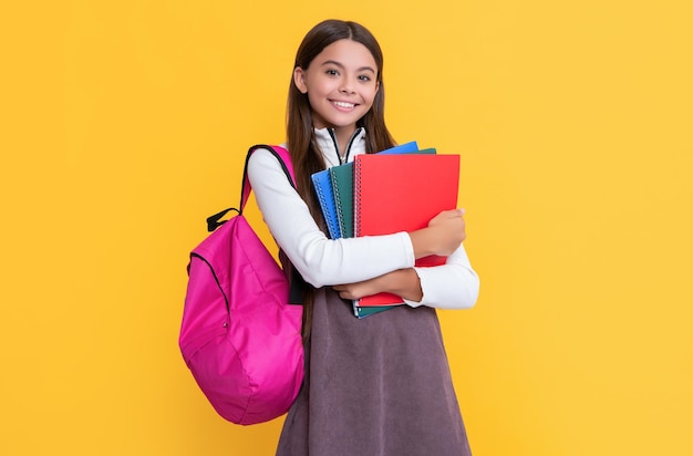 Bambino positivo con zaino scolastico e cartella di lavoro su sfondo giallo