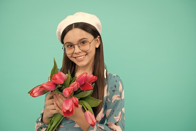 Bambino positivo in berretto con tulipani madri o giorno delle donne bambino in bicchieri tengono fiori