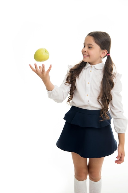 Bambino ragazza scuola uniforme vestiti lancio mela Ragazza carina pupilla tiene mela frutta sfondo bianco Bambino intelligente ragazzo sorridente faccia scegliere uno spuntino sano Pranzo a scuola spuntino concetto Alimentazione sana