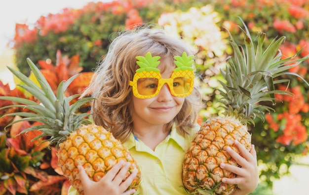 Bambino ragazzo azienda ananas sorridente con la faccia felice in cortile Frutta estiva