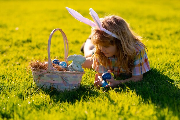 Bambino ragazzo caccia uova di Pasqua Bambino carino in costume da coniglio con orecchie da coniglio che hanno Pasqua nel parco I bambini cacciano l'uovo di Pasqua