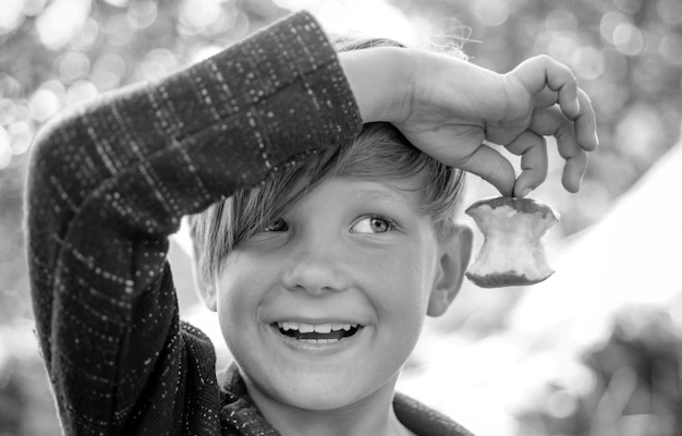 Bambino ragazzo che tiene foglia d'oro e si trova sul fieno bambino in una vacanza autunnale nella fattoria di nuovo a scuola a