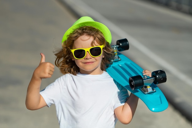 Bambino ragazzo che tiene longboard su strada bambino con pennyboard all'aperto ritratto all'aperto di allegro littl