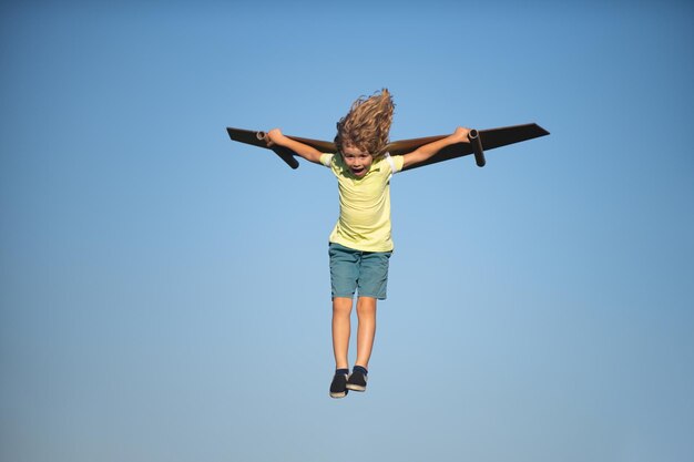 Bambino ragazzo come un pilota con ali giocattolo contro il cielo blu bambini concetto di libertà startup