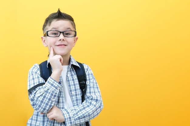 Bambino ragazzo con gli occhiali isolato su carta gialla parete Grande idea Scolaro sorridente felice torna a scuola Concetto di genio vincitore di motivazione di successo