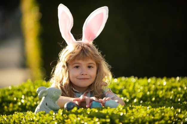 Bambino ragazzo con uova di Pasqua all'aperto Caccia alle uova di Pasqua Fynny Kids faccia Felice giorno di Pasqua Bambino con orecchie da coniglio