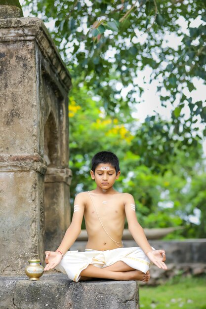 Bambino sacerdote indiano che fa yoga al parco