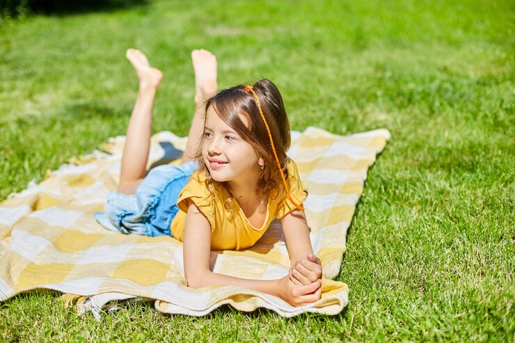 bambino sdraiato sulla coperta, sull'erba in una giornata di sole, la bambina prende il sole nella casa del cortile