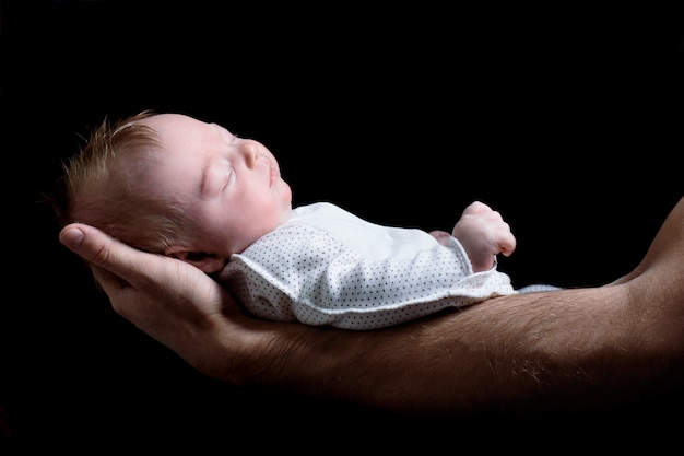 Bambino sdraiato sulle braccia del padre. Neonato e papà. Vista laterale, primo piano isolato