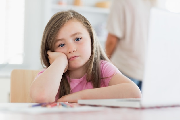 Bambino seduto al tavolo che sembra annoiato