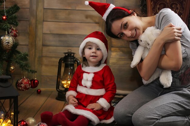 Bambino seduto davanti a un albero di Natale e gioca con i giocattoli