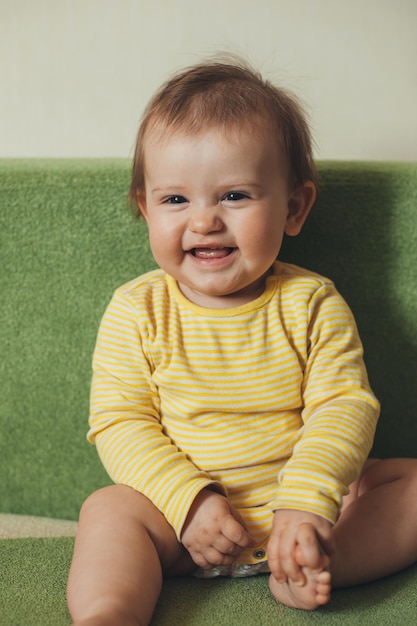 Bambino seduto sul divano e sorridente alla vista frontale della telecamera neonato caucasico