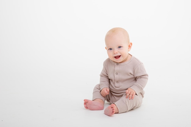 Bambino seduto sul pavimento isolato su sfondo bianco per studio