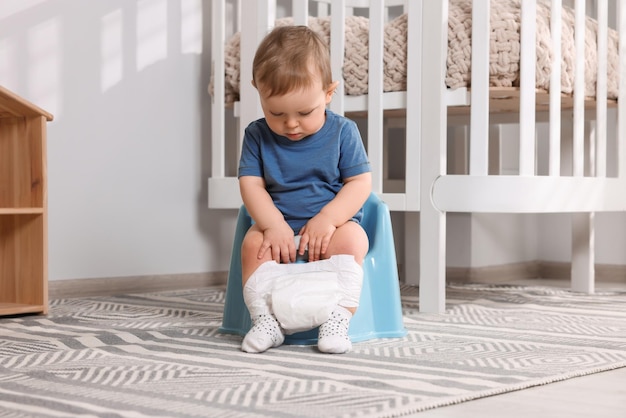 Bambino seduto sul vasino di plastica per bambini al chiuso