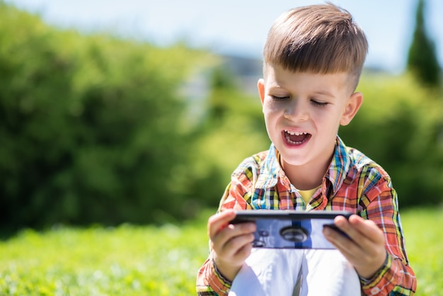 bambino seduto sull'erba alla ricerca sul telefono