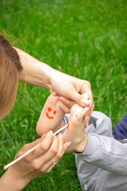 Bambino seduto sull'erba, sorridente sulla gamba del bambino con la vernice