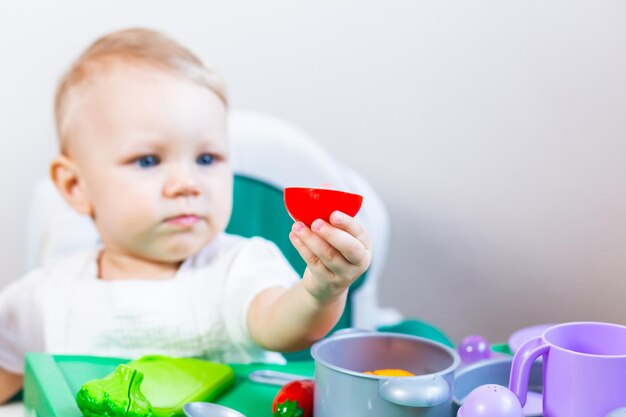 Bambino sfocato che tiene in mano una verdura giocattolo sullo sfondo dei piatti