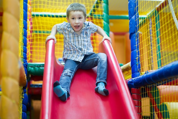 Bambino soddisfatto su una collina per bambini nel centro di intrattenimento Il bambino nel centro di intrattenimento