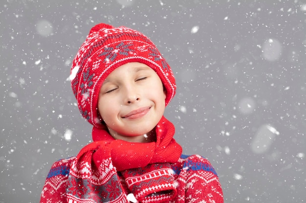 Bambino sognante in abiti caldi su uno sfondo invernale