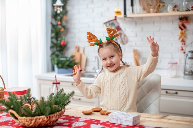 Bambino sognante in maglione leggero e cerchietto con corna di renna