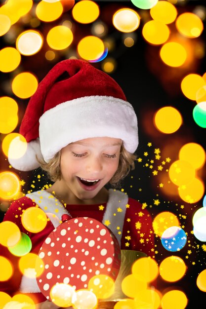 Bambino sorpreso che tiene il contenitore di regalo di Natale. bambino felice che si diverte a casa. Concetto di vacanza di Natale