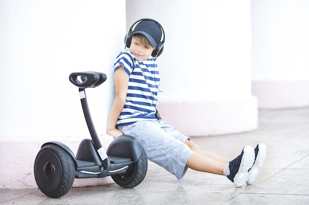 Bambino sorridente che guida trasporto elettrico. Gioventù attiva. Ragazzo carino all'aperto.