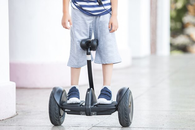 Bambino sorridente che guida trasporto elettrico. Gioventù attiva. Ragazzo carino all'aperto.