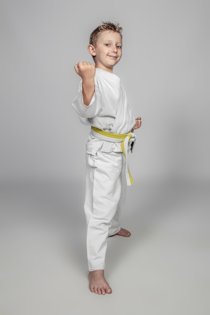 Bambino sorridente che pratica arti marziali che indossa un judogi.