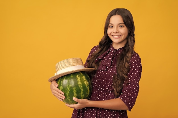 Bambino sorridente che tiene frutta fresca di anguria matura in salute del cappello di paglia di estate