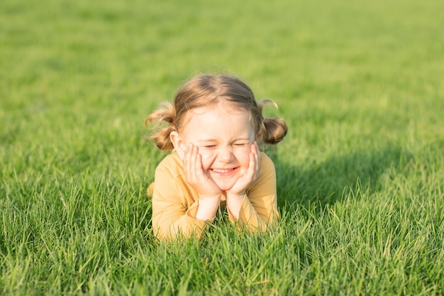 bambino sorridente chiudi gli occhi sdraiato sull'erba verde e soleggiata per rilassarti e goderti lo sfondo dell'erba della natura