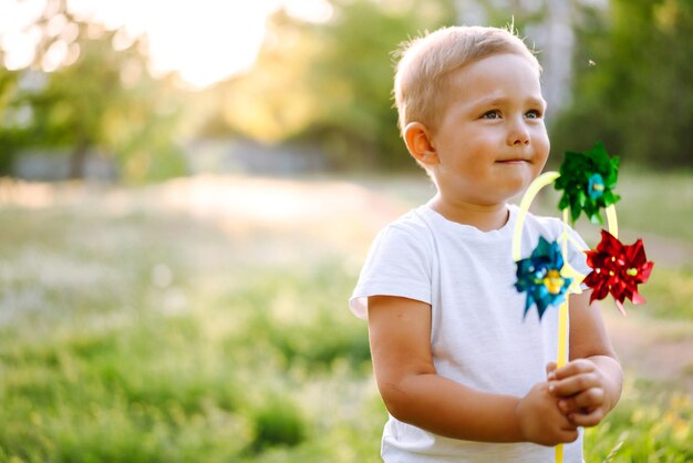 Bambino sorridente con giocattolo nel parco estivo in giornata di sole Ragazzino carino che gode del fresco clima primaverile