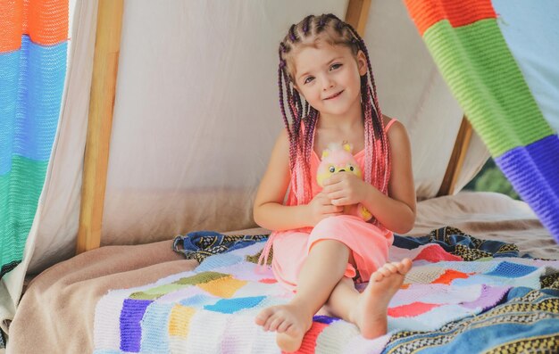 Bambino sorridente con i dreadlocks in tenda Ragazza che gioca in tenda bambino in campeggio divertendosi all'aperto a campgr