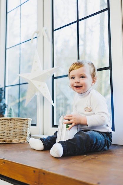 Bambino sorridente di 1 anno sullo sfondo delle decorazioni natalizie a casa Atmosfera di Capodanno a casa