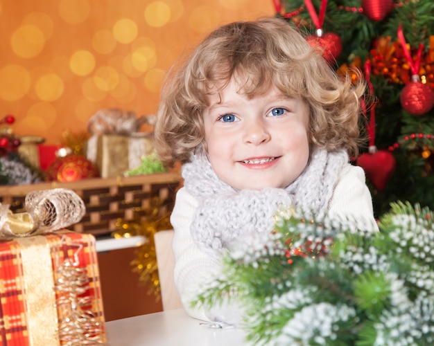 Bambino sorridente felice contro l'albero di Natale con decorazioni