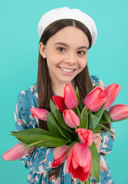 Bambino sorridente in berretto con tulipani madri o festa della donna bambino in possesso di fiori per l'8 marzo