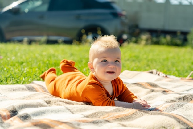 Bambino sorridente sdraiato sulla coperta sull'erba estiva