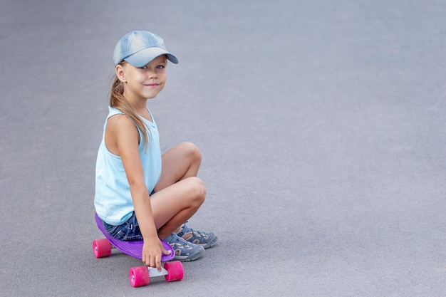 Bambino sorridente seduto su skateboard su strada
